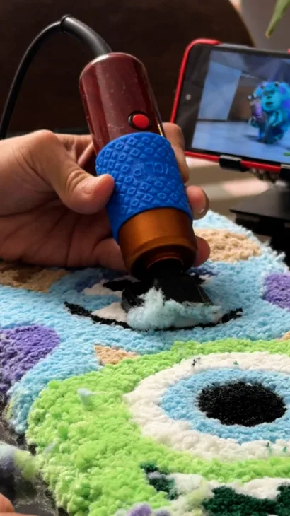 Esculpiendo con una recortadora el ojo de Mike Wazowski en un tapete de tufting