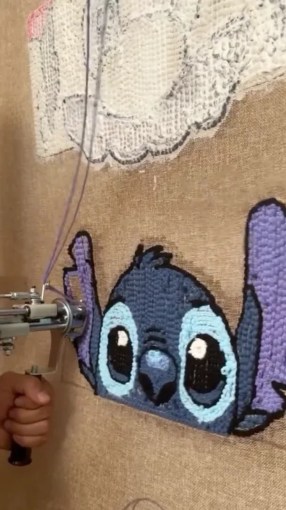 Pistola de tufting rellenando de lana azul la cara de Stitch sobre la tela